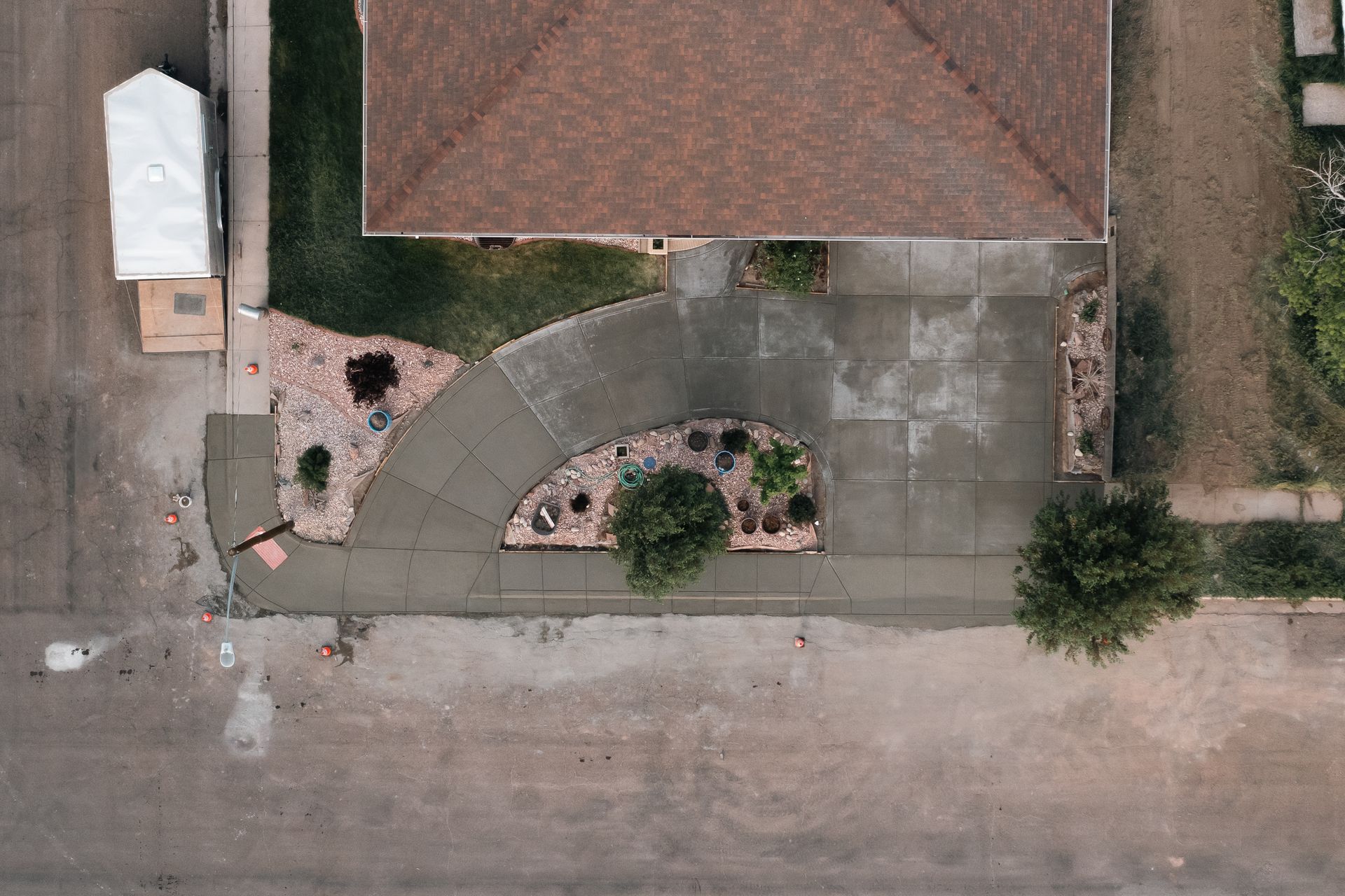 Aerial view of house with brown roof and curved concrete driveway.