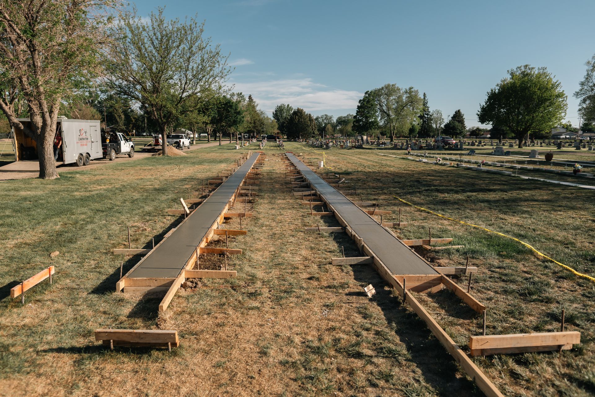 Concrete forms set in a grassy cemetery, preparing for a path or walkway.