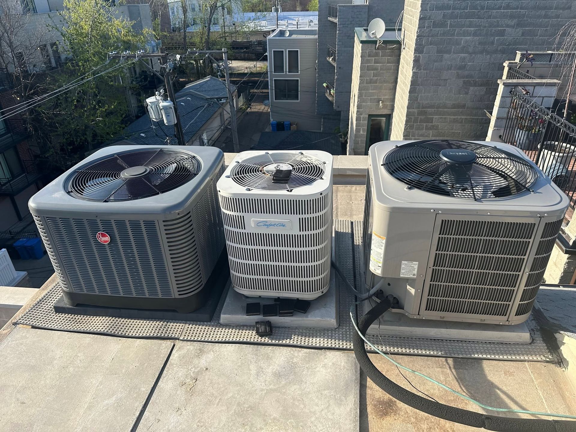 Three rooftop HVAC units with fans on a building, viewed from above.