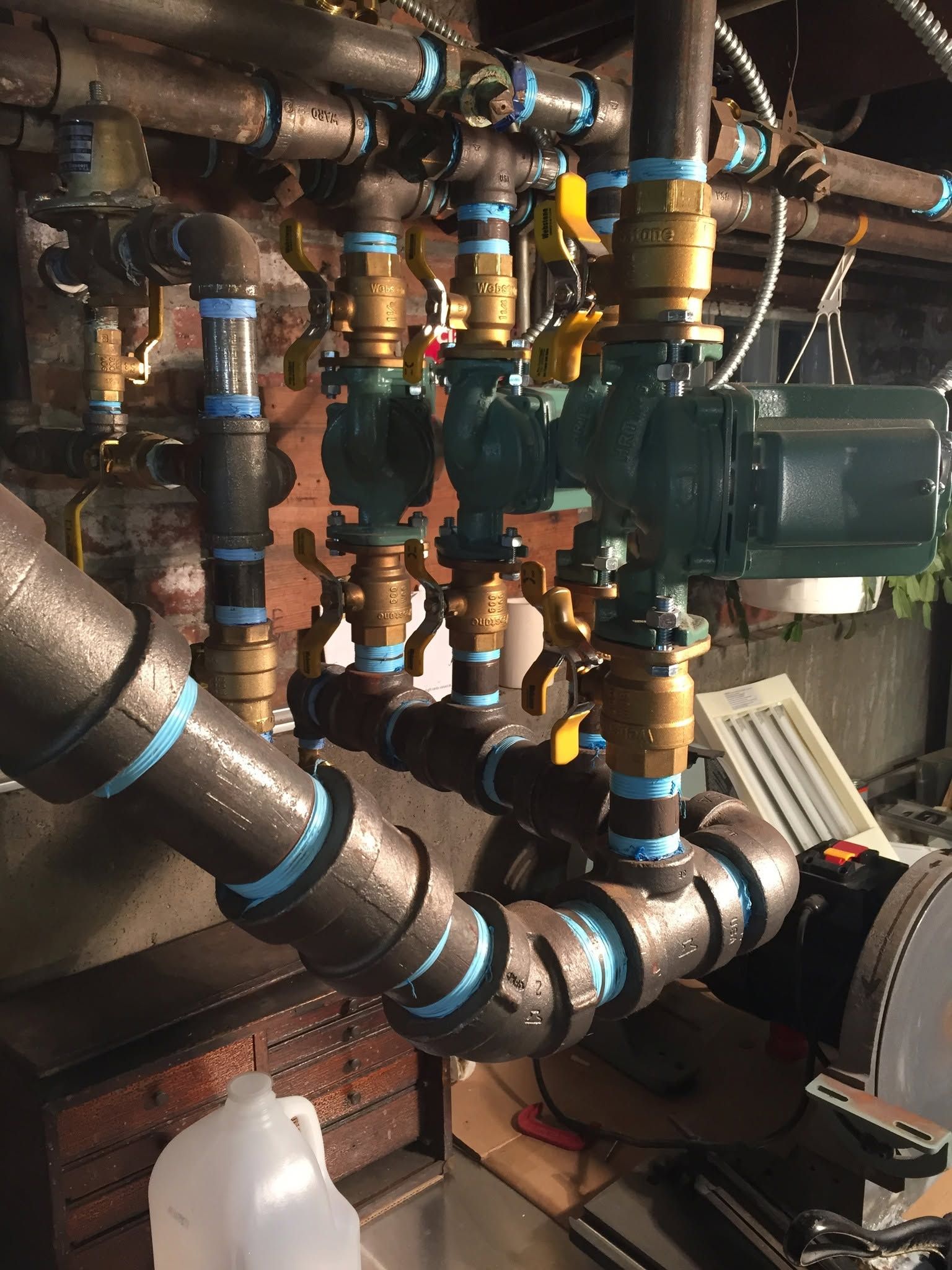 Industrial piping and valves connected to a large green pump in a mechanical room