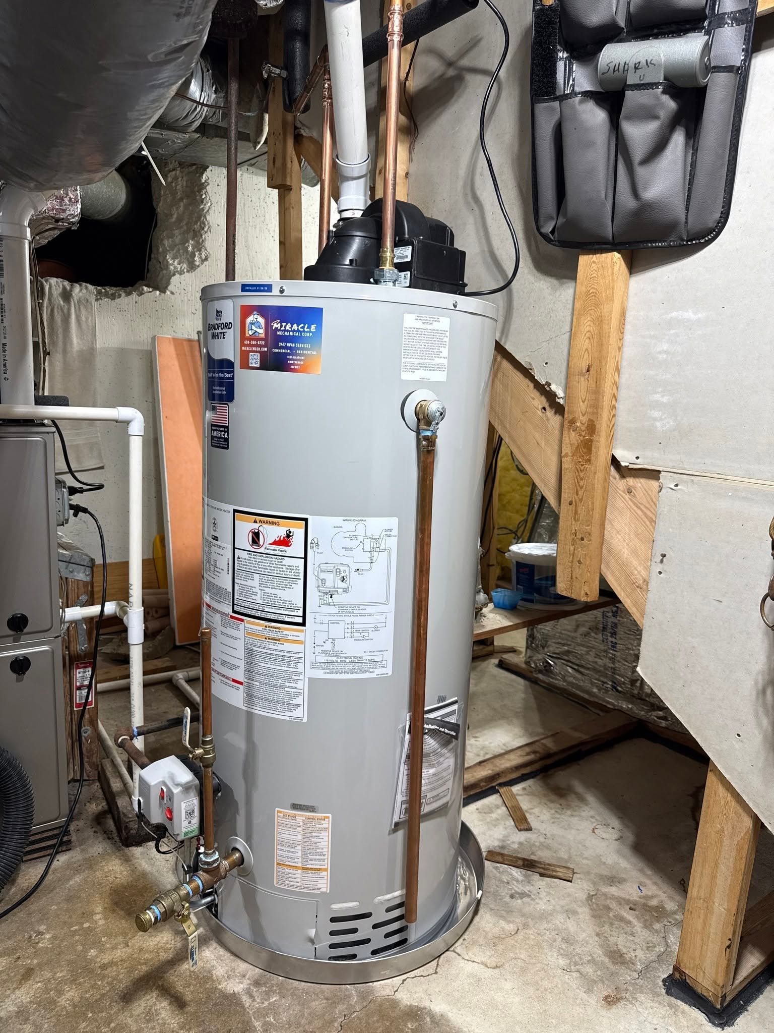 Water heater in a basement utility area with exposed pipes, vents, and unfinished framing.