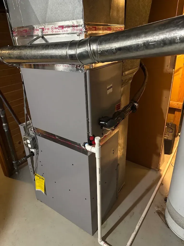 Residential furnace with silver ductwork and wiring in a utility closet