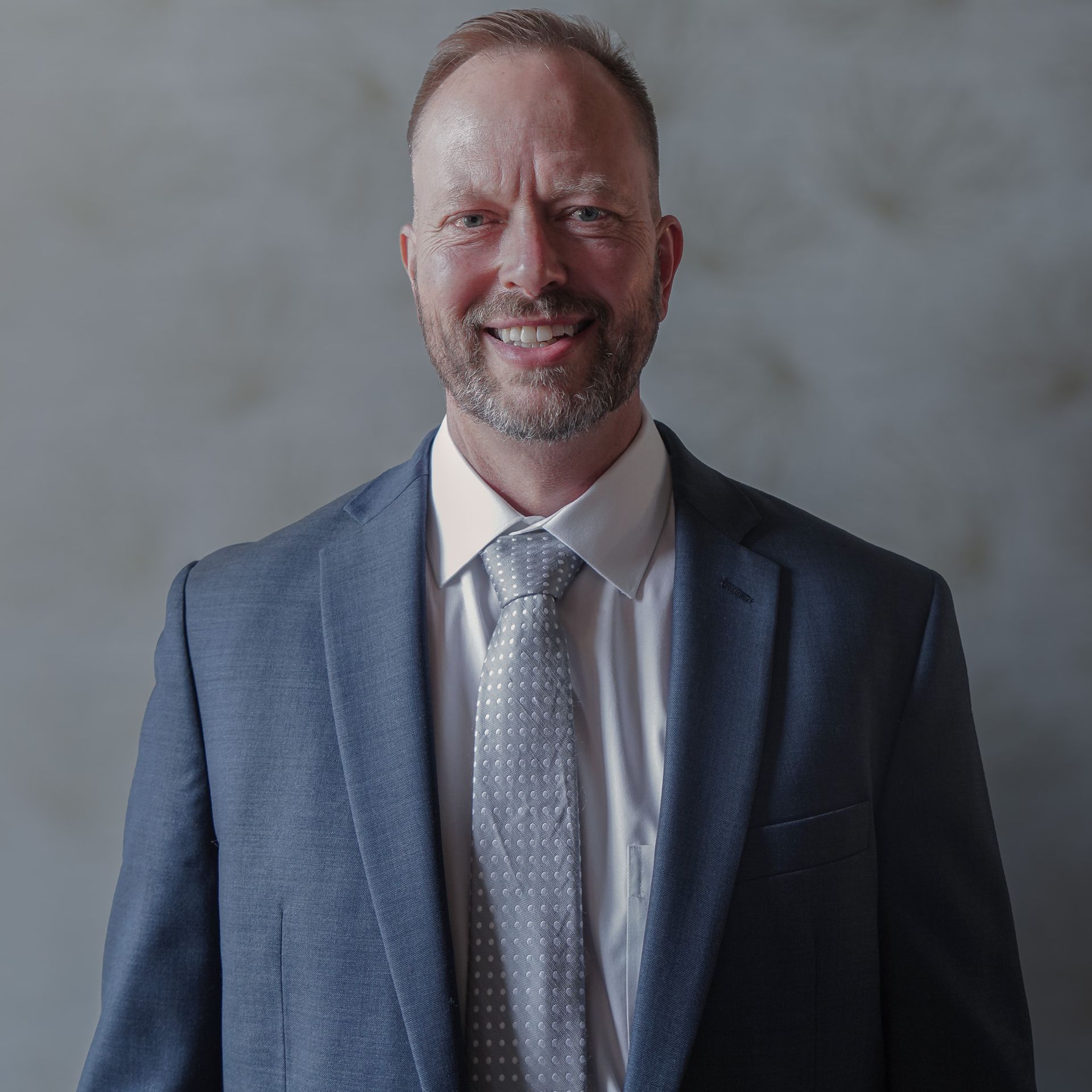 A man in a suit and tie is smiling for the camera.
