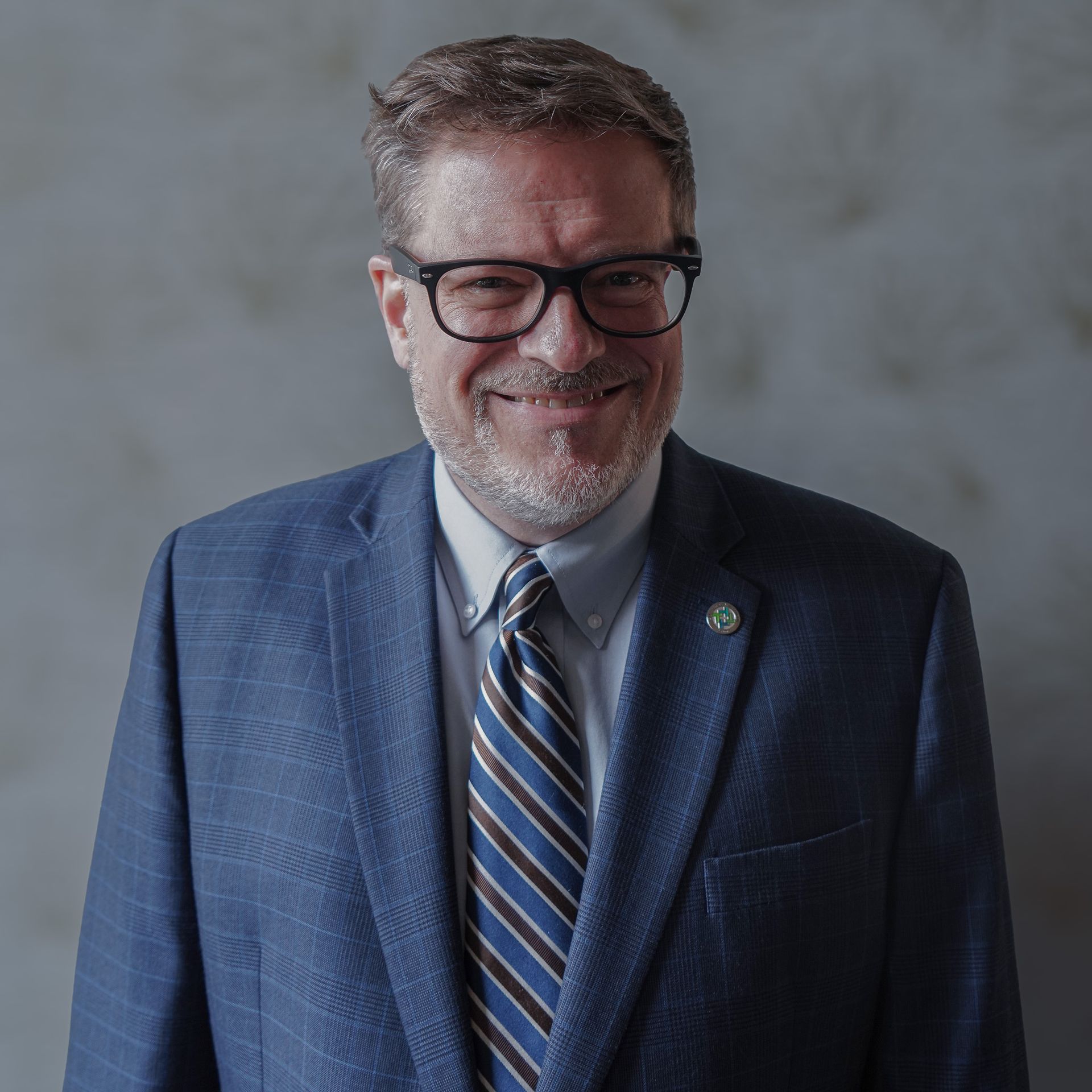 A man in a suit and tie is smiling for the camera