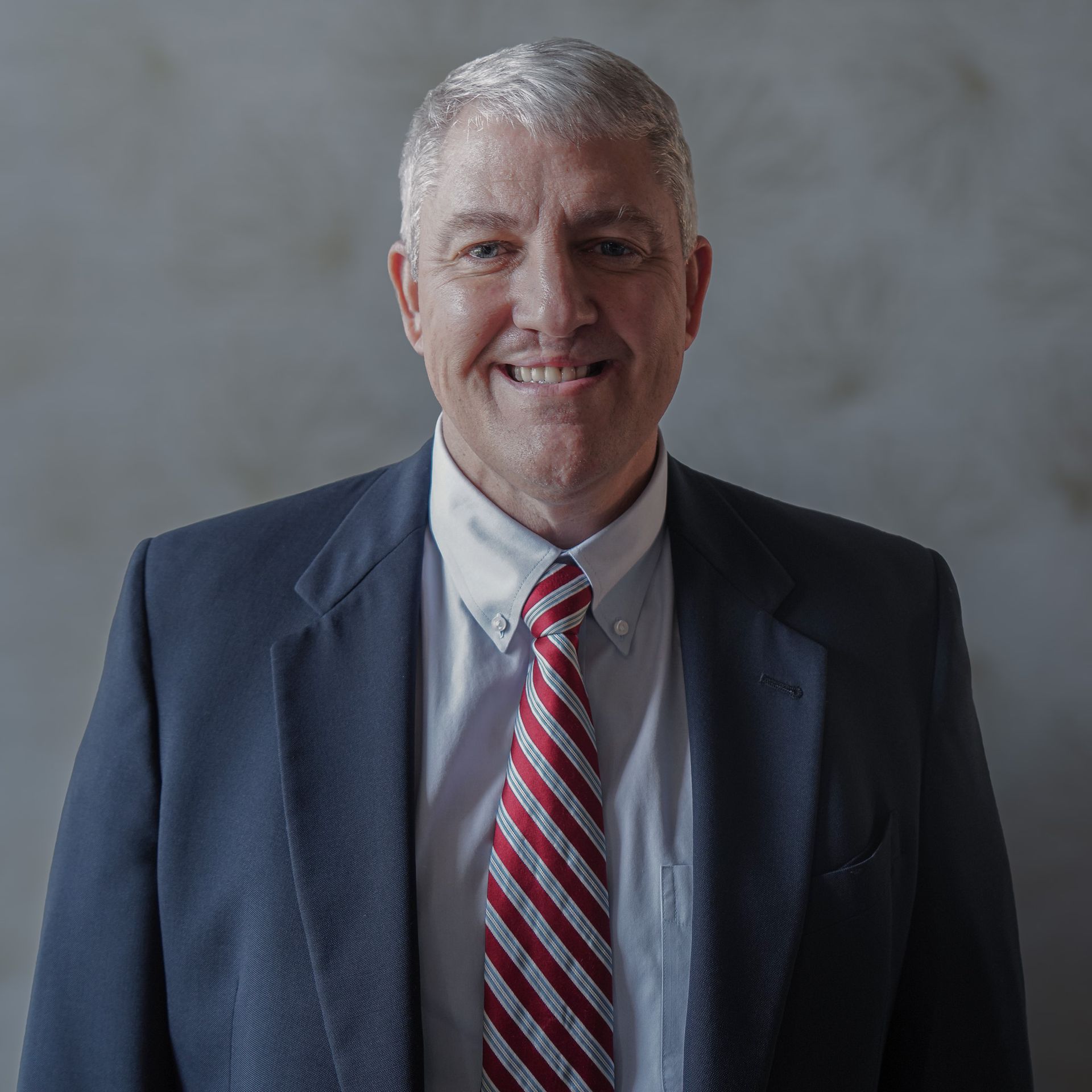A man in a suit and tie is smiling for the camera.