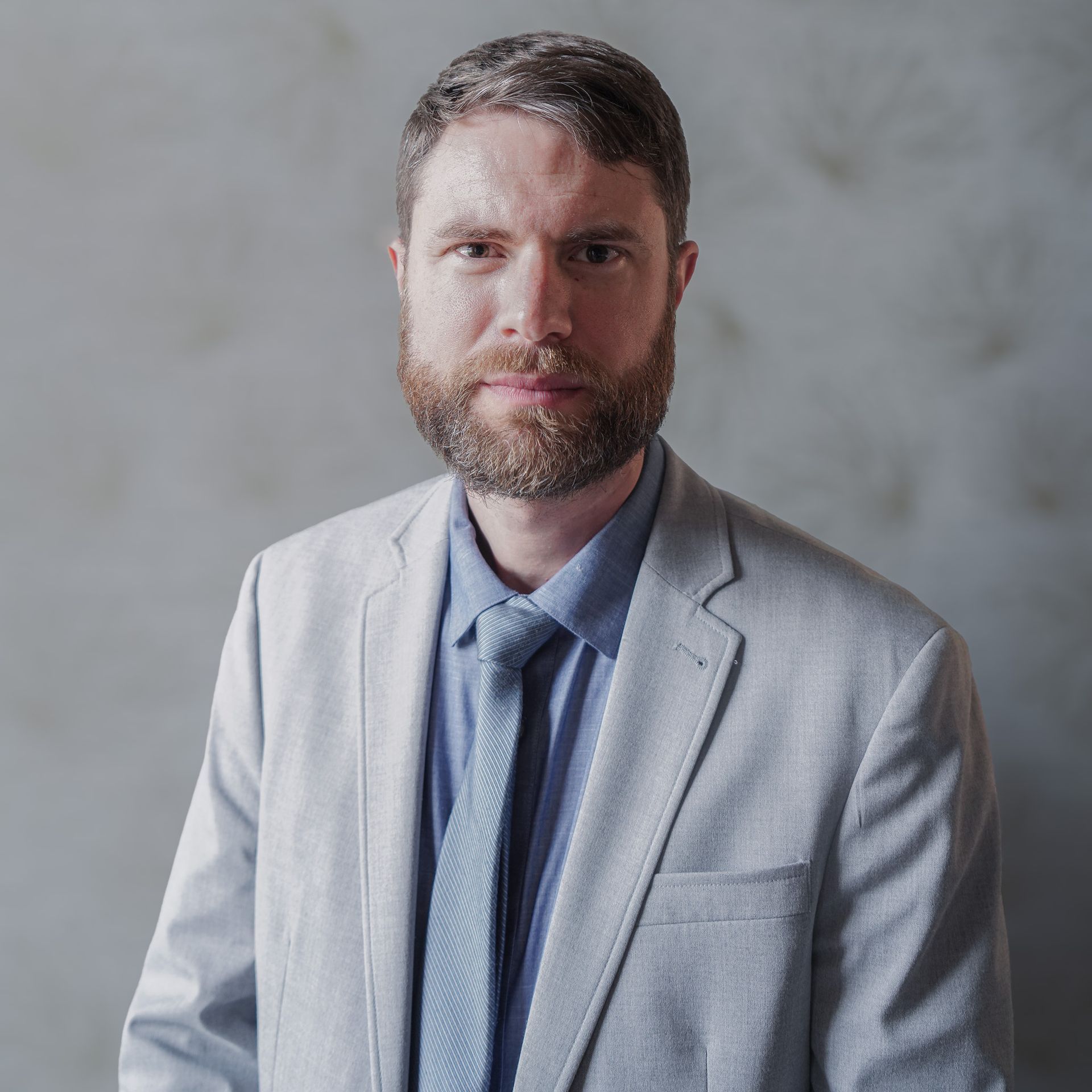 A man with a beard is wearing a suit and tie.