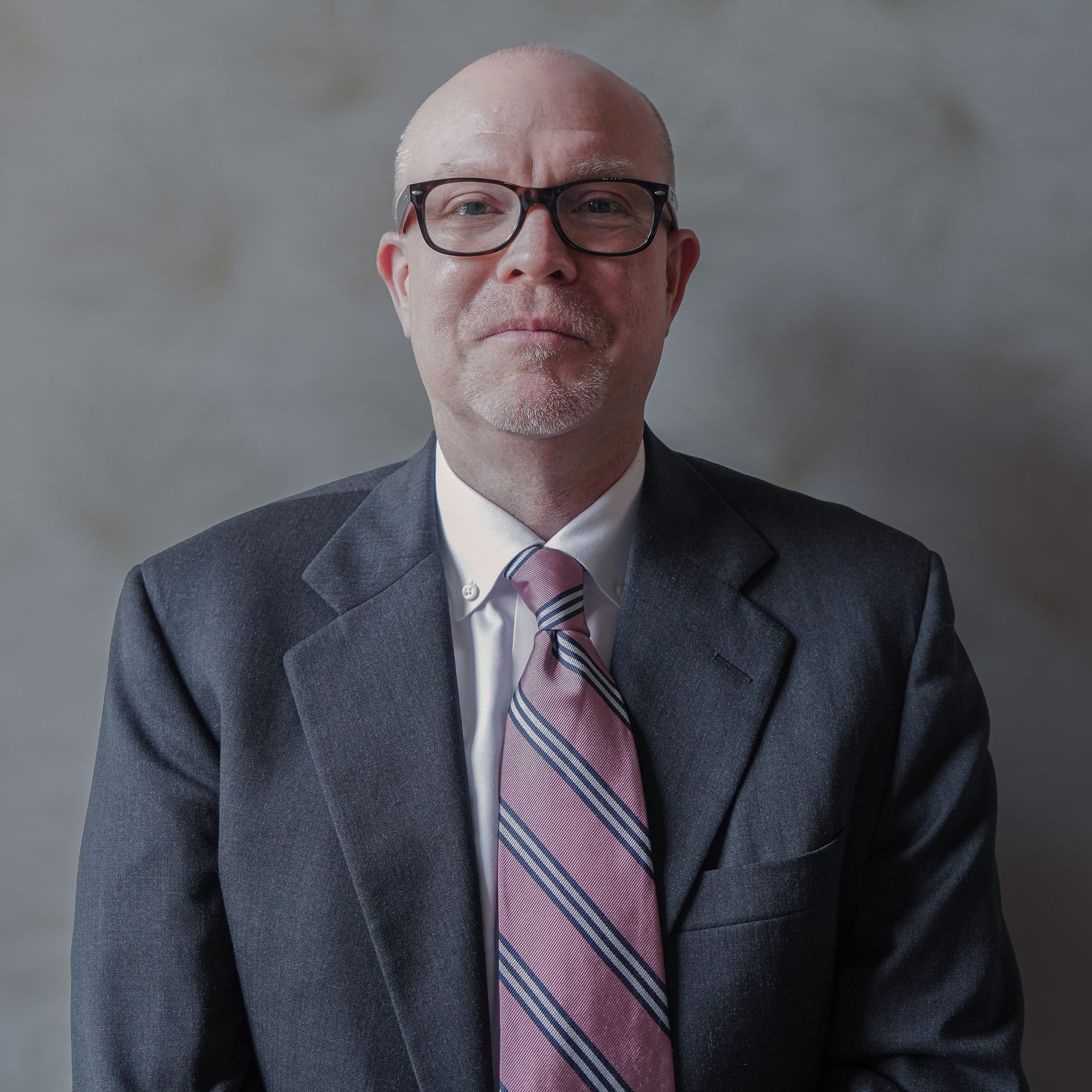 A bald man wearing glasses and a suit and tie