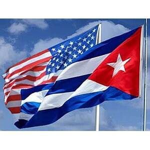 U.S. and Cuban flags waving side by side against a blue sky
