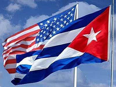 U.S. and Cuban flags waving side by side against a blue sky
