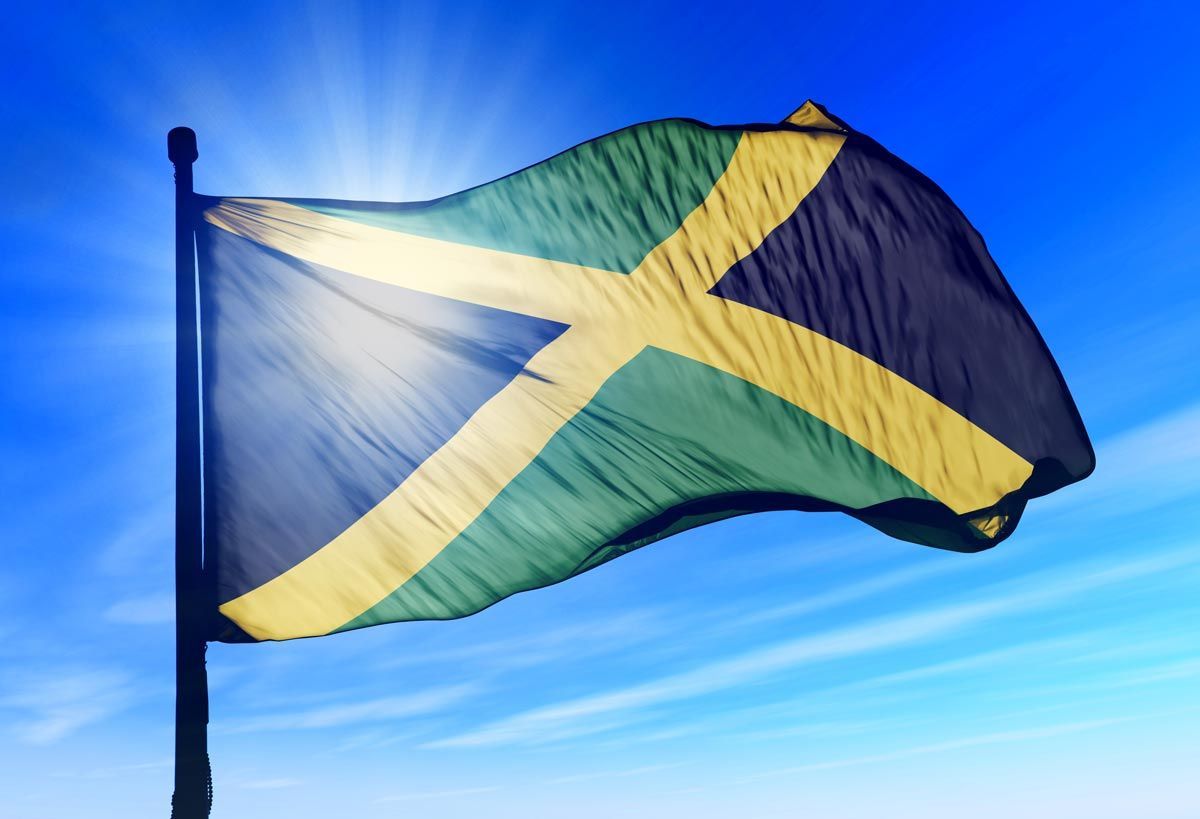 Jamaican flag waving against a bright blue sky
