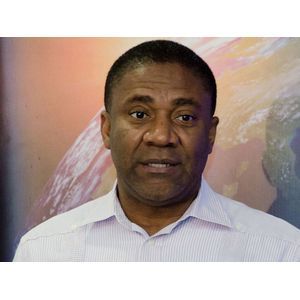 Portrait of a man in a white shirt standing before a colorful globe backdrop