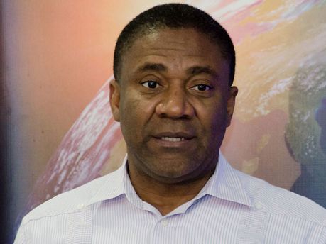Man speaking in a white shirt against a colorful globe backdrop.