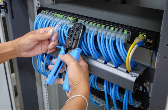 Hands organizing blue network cables in a server rack cabinet