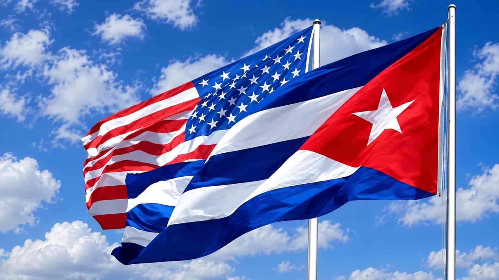 U.S. and Cuban flags waving side by side against a blue sky
