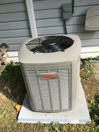 Outdoor Lennox air conditioner unit on a concrete pad beside a house wall.