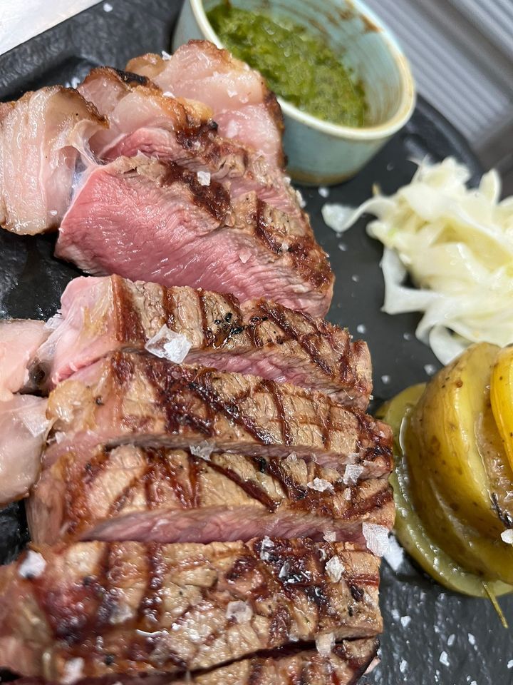Fettine di bistecca grigliate con salsa verde, cipolle sottaceto e peperoni banana su un piatto