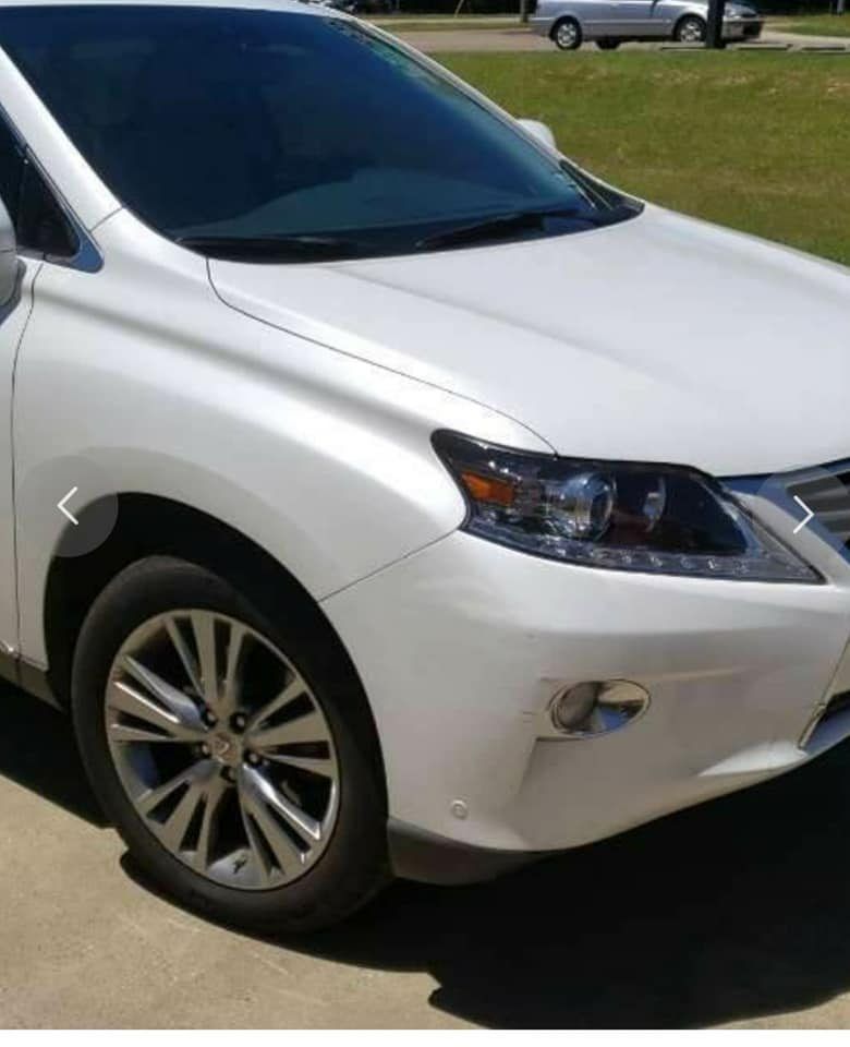 A white Lexus SUV parked on a paved driveway, viewed from a high angle focusing on the front passenger side.