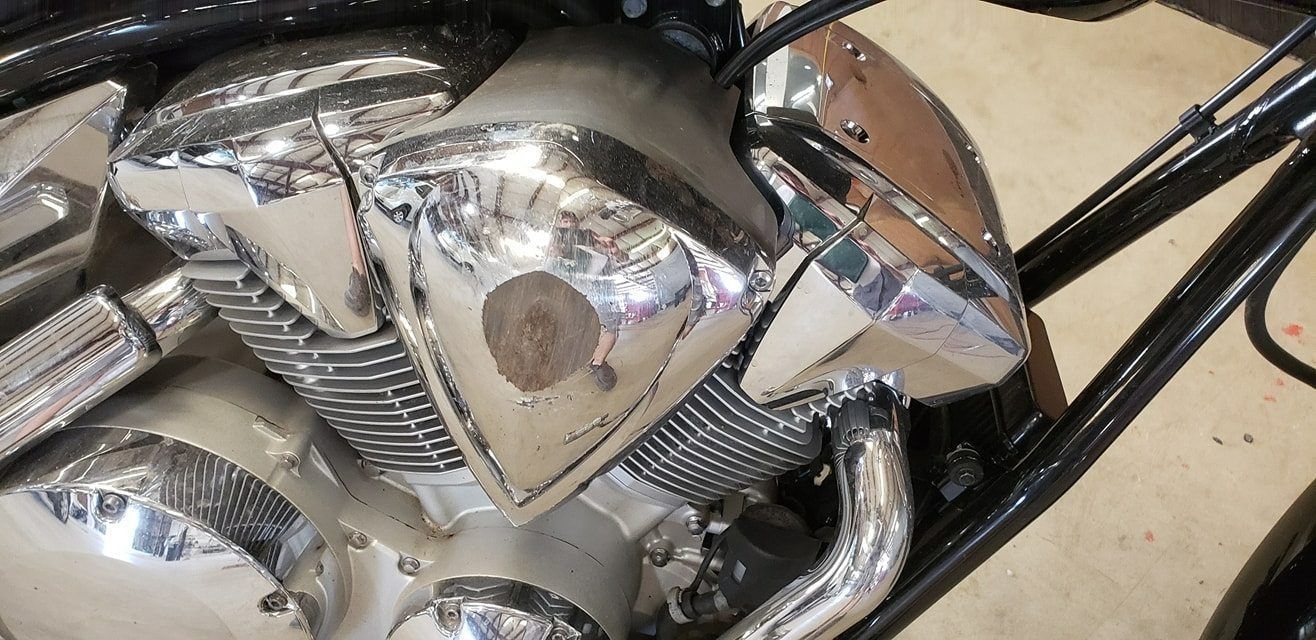 Close-up of a polished chrome motorcycle engine with a triangular side cover and black frame components.
