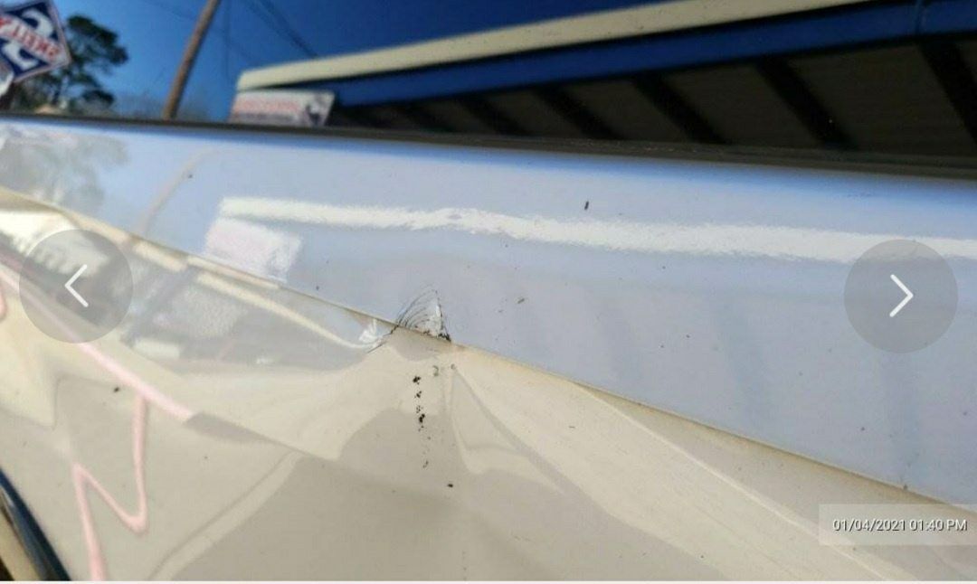 A close-up view of a vehicle's body panel showing a dent and paint damage along the edge.