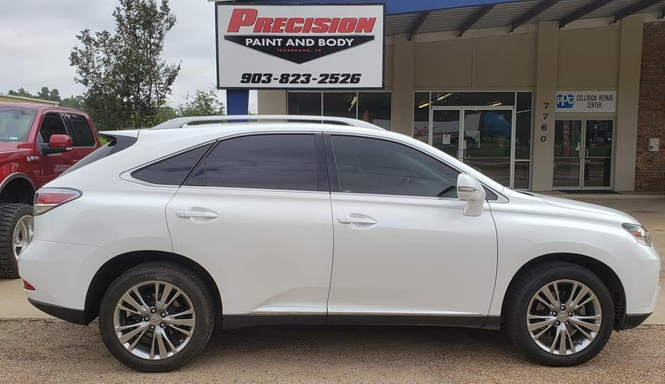 A white Lexus SUV parked in front of a Precision Paint and Body shop with a prominent sign above.