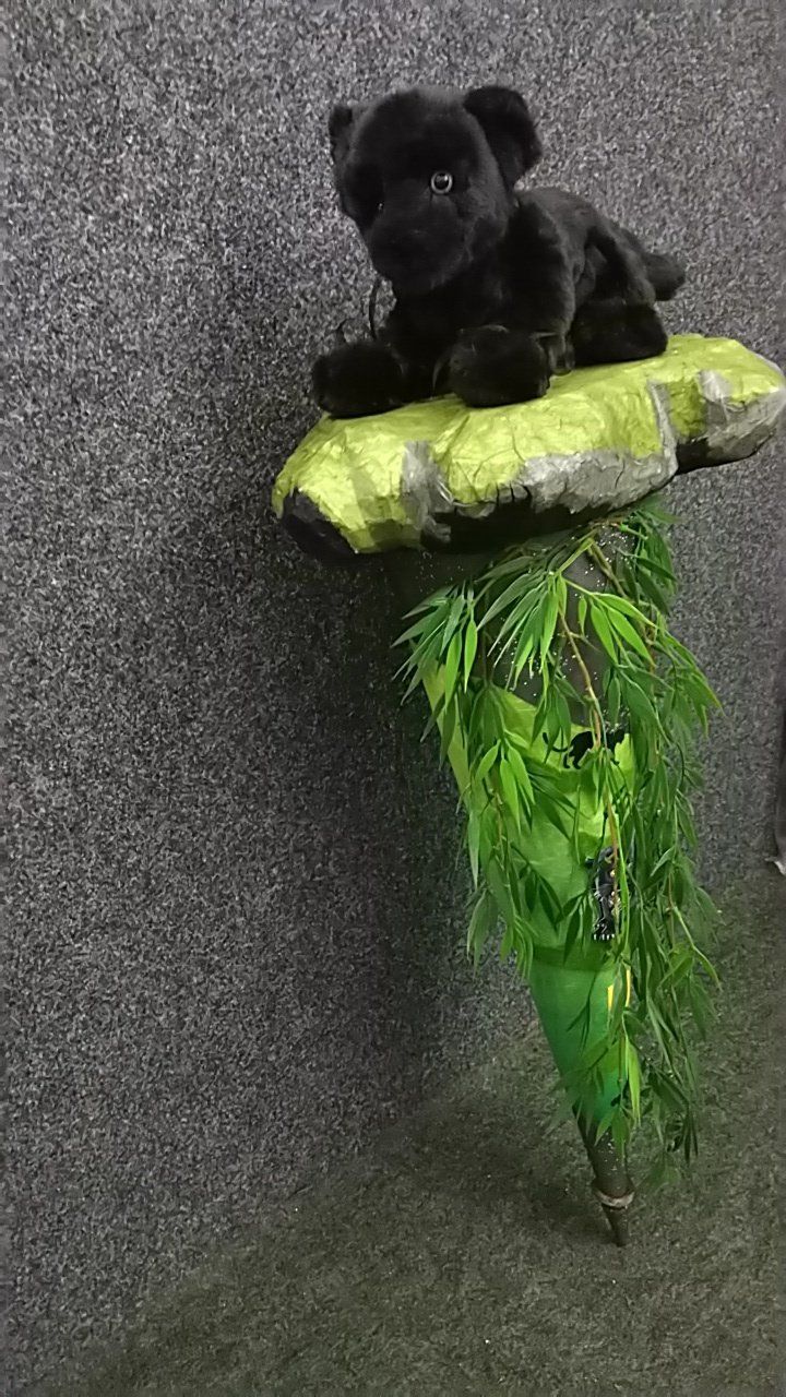 Ein ausgestopfter schwarzer Panther sitzt auf einem Felsen.