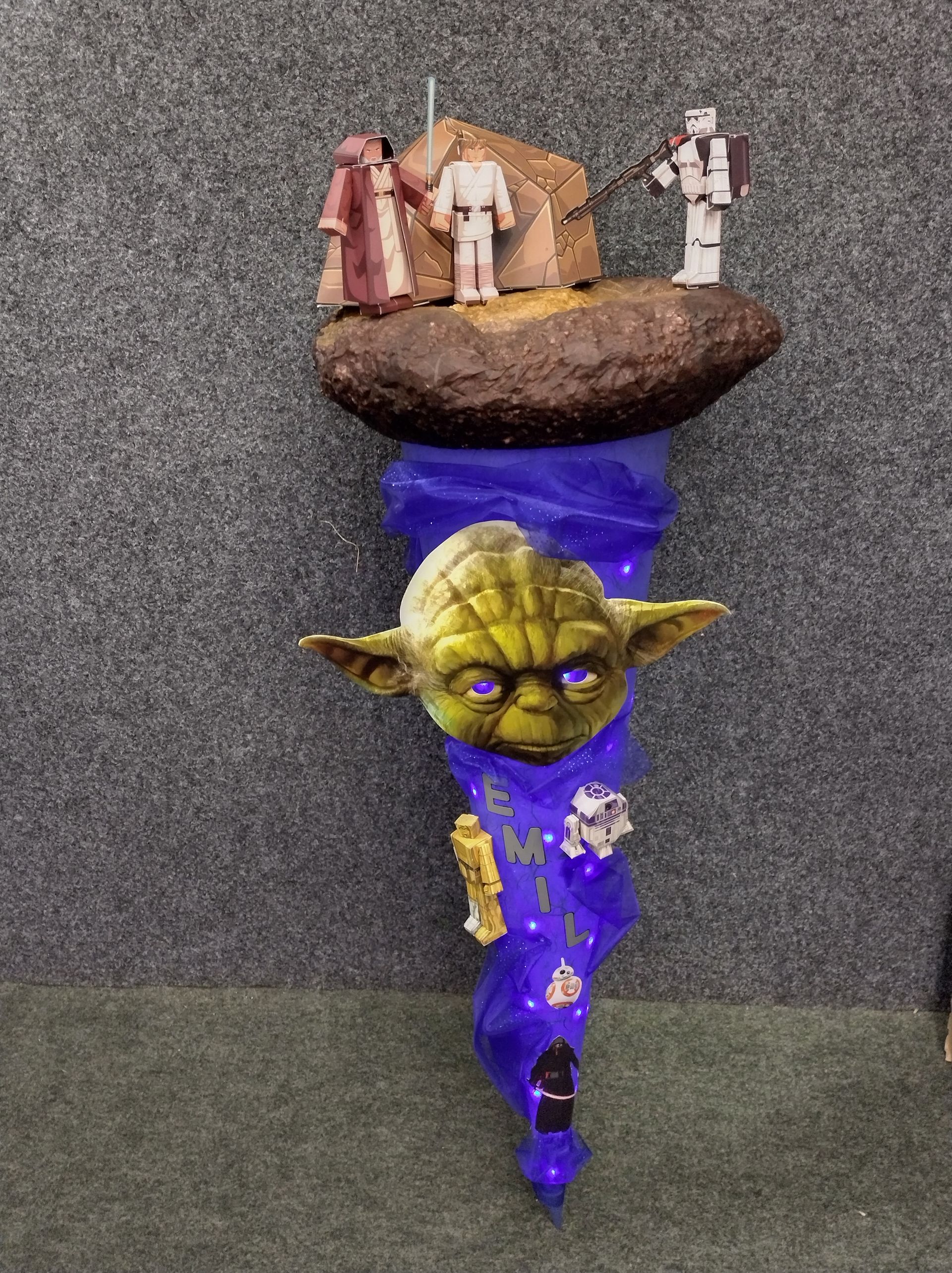 Eine Yoda-Statue sitzt auf einem violetten Gegenstand.