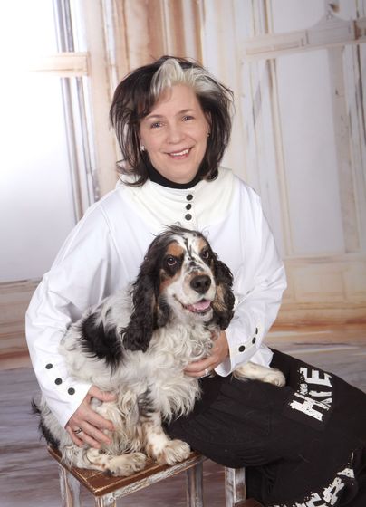 Eine Frau in einer grünen Jacke sitzt neben einem schwarz-weißen Hund.