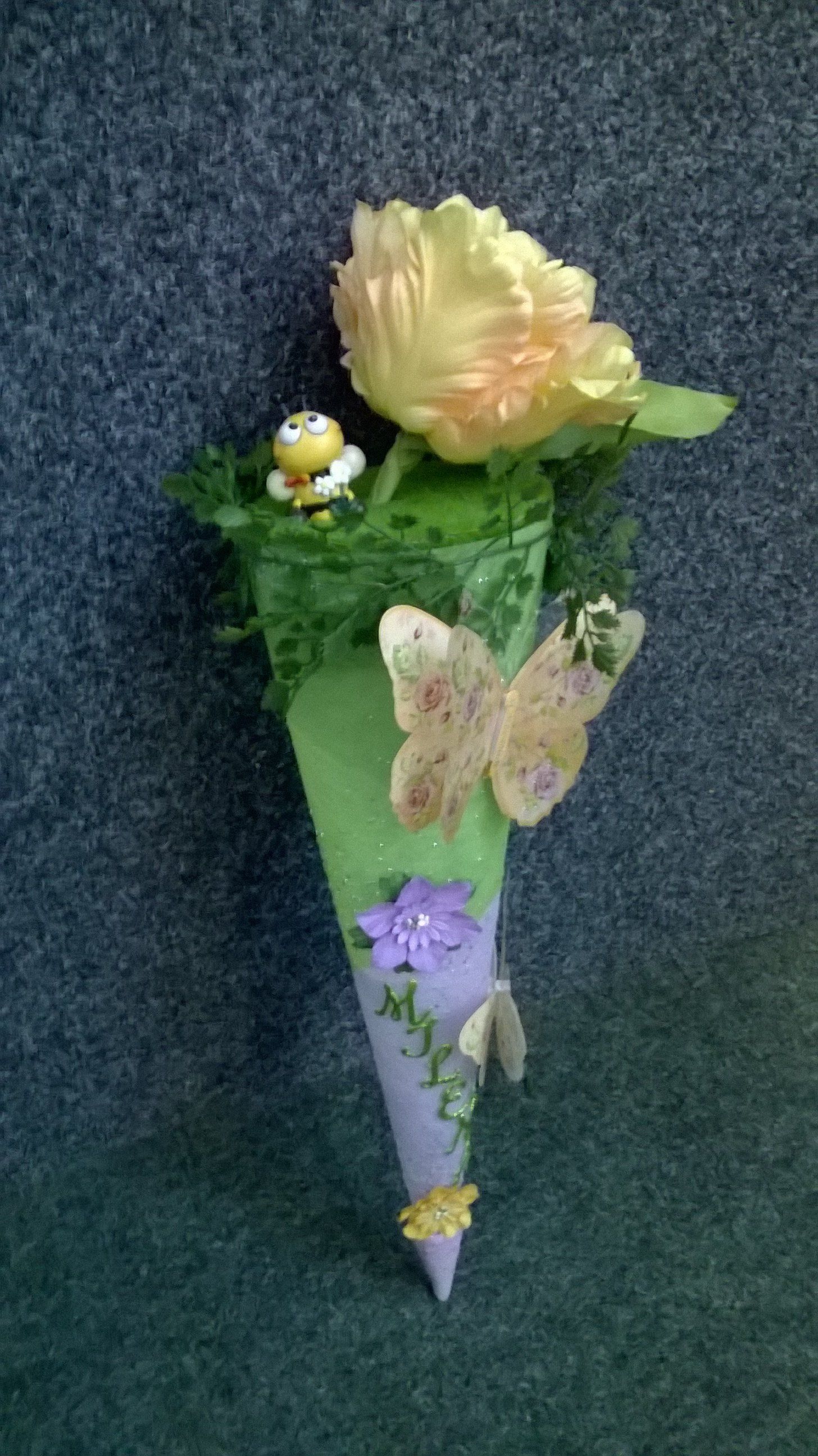 Ein Kegel gefüllt mit Blumen und Schmetterlingen auf einem Tisch.