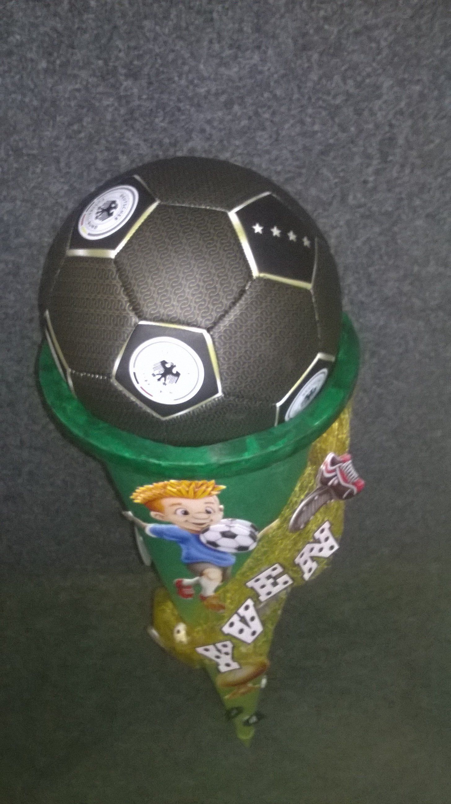 Ein Fußball liegt auf einem grünen Kegel.