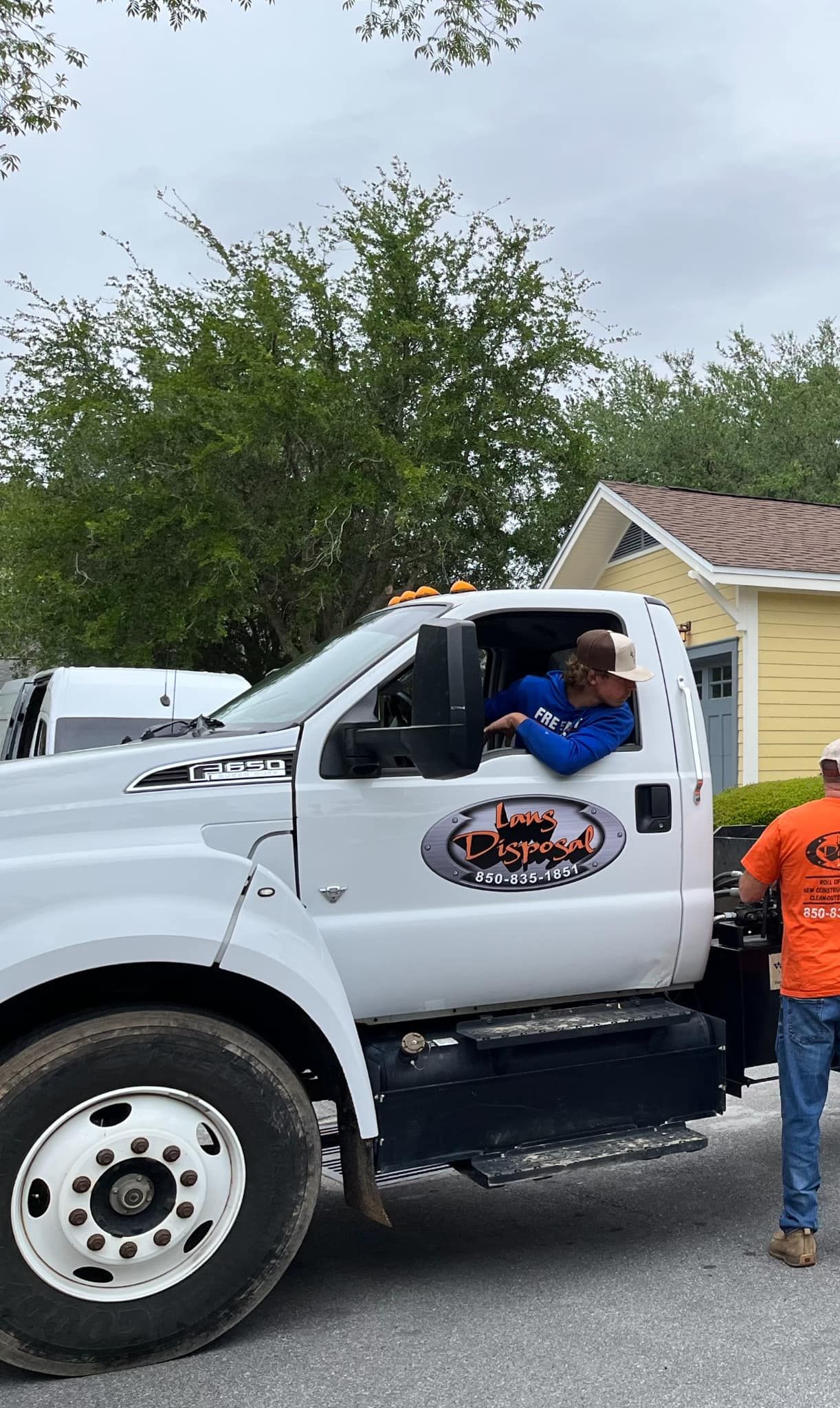 White pickup truck with a driver in blue shirt and a child standing beside it outdoors