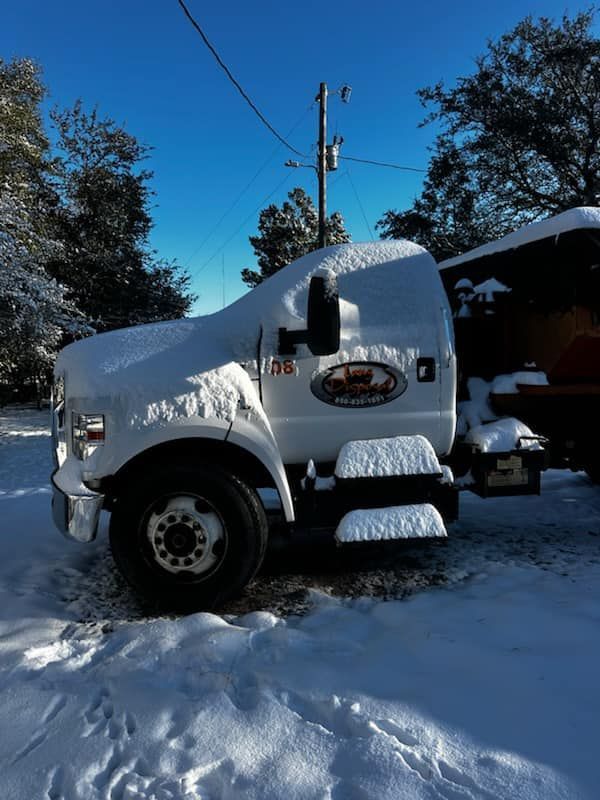 White semi-truck buried in snow on a snowy road under a clear blue sky
