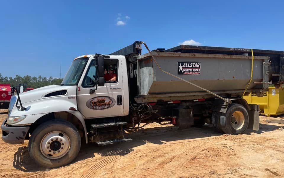 White dump truck with a silver bed parked on a dirt lot under a blue sky