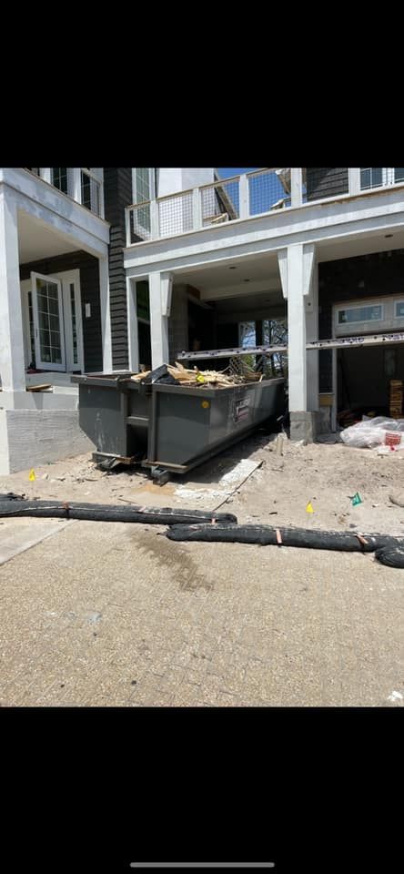 Dumpster overflowing with debris outside a building entrance, with trash scattered on the sidewalk.