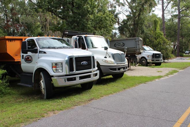 White utility trucks parked along a roadside in a wooded area White utility trucks parked along a roadside in a wooded area