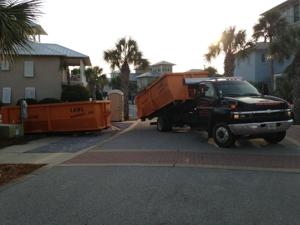 Black truck with orange dumpster bins blocking a gated driveway in a residential neighborhood
