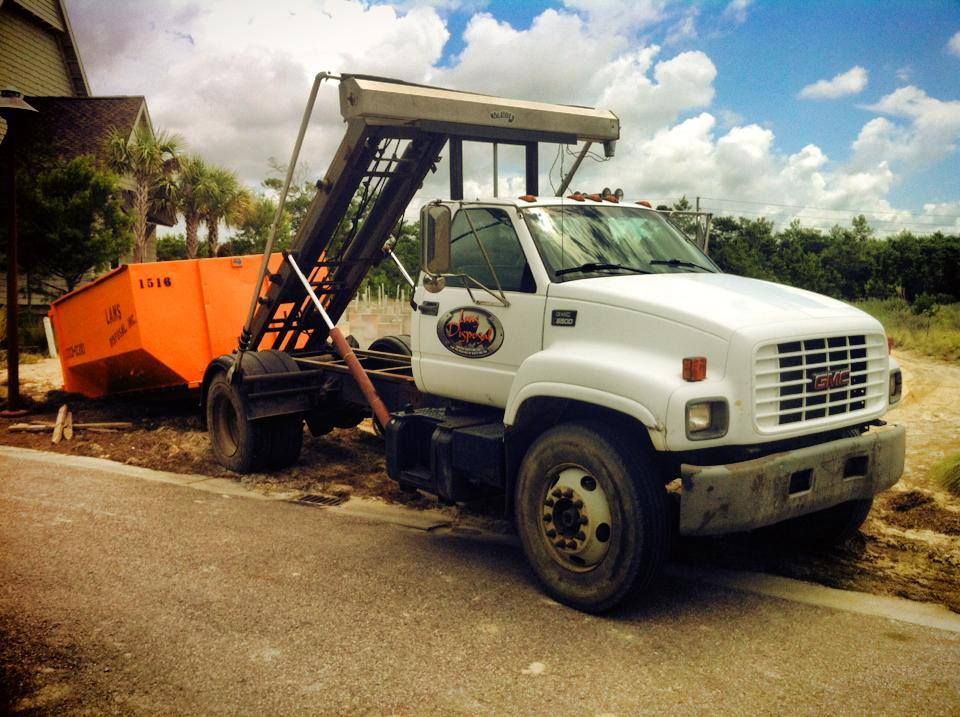 White dump truck with orange bed parked beside a road under a cloudy sky