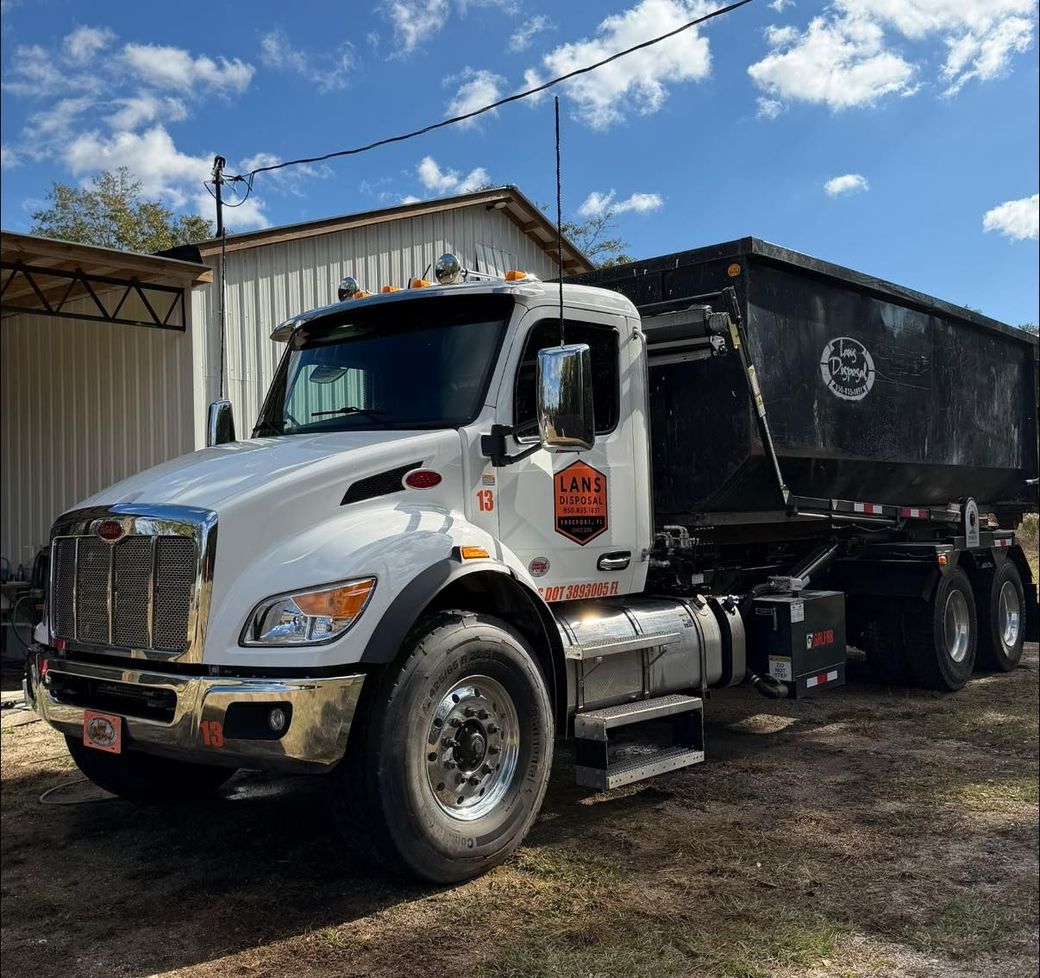 White semi-truck with black dump trailer parked outside under a blue sky White semi-truck with black dump trailer parked outside under a blue sky