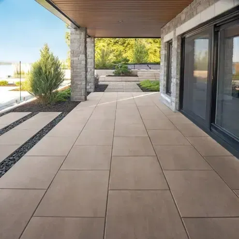 A patio with a bar and stools under a pergola.