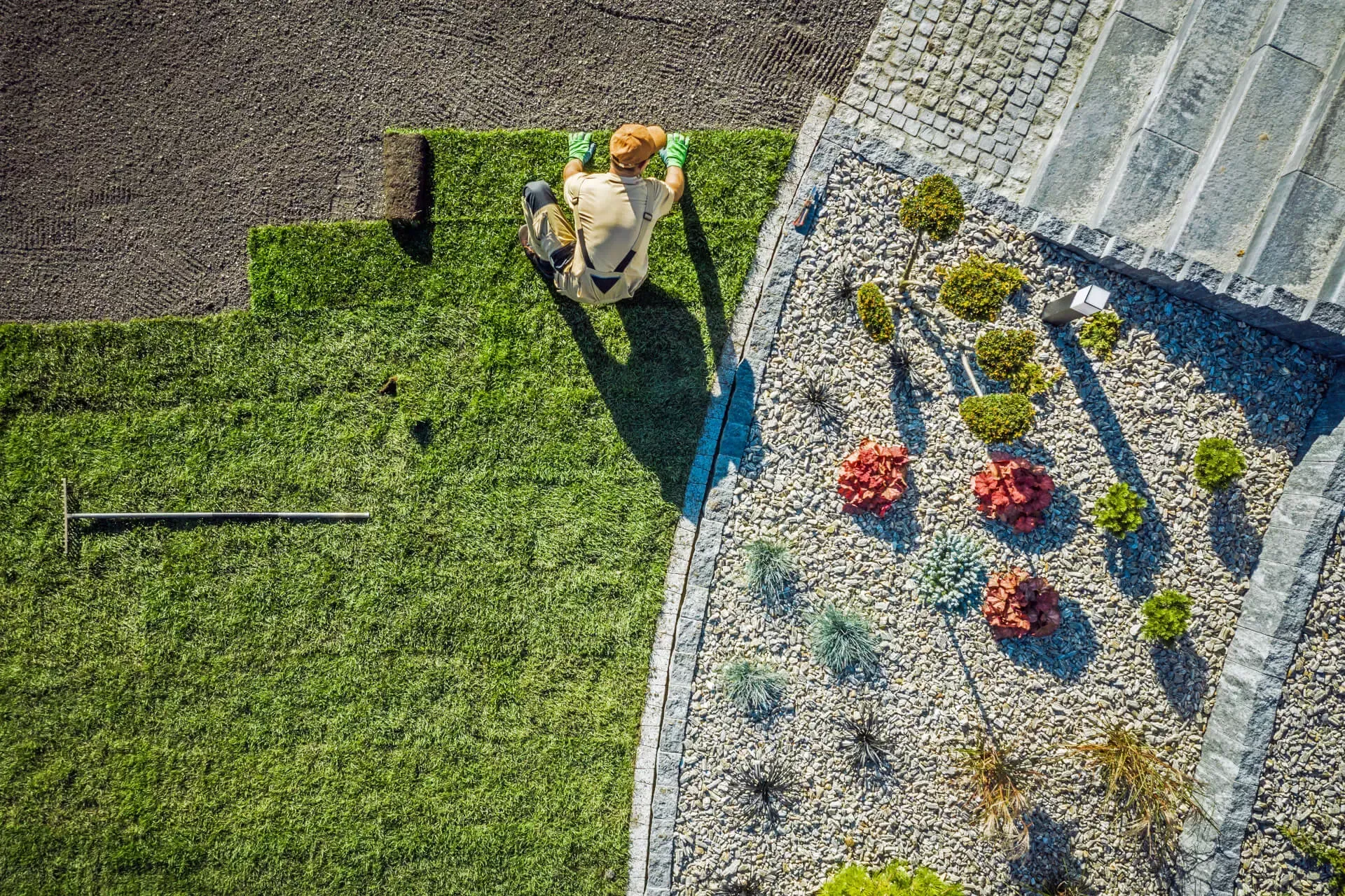 An aerial view of a man cutting grass in a garden.