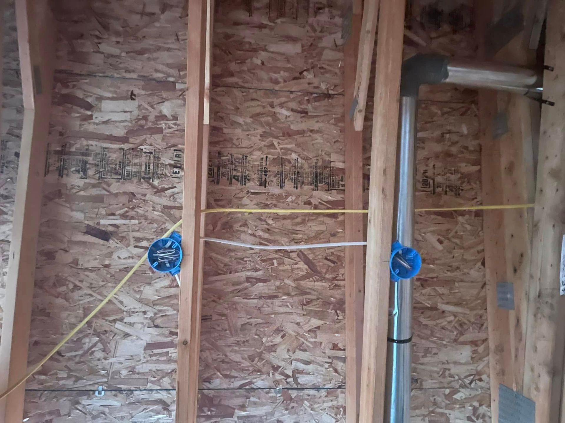 Exposed wall framing with electrical boxes and conduit in an unfinished room