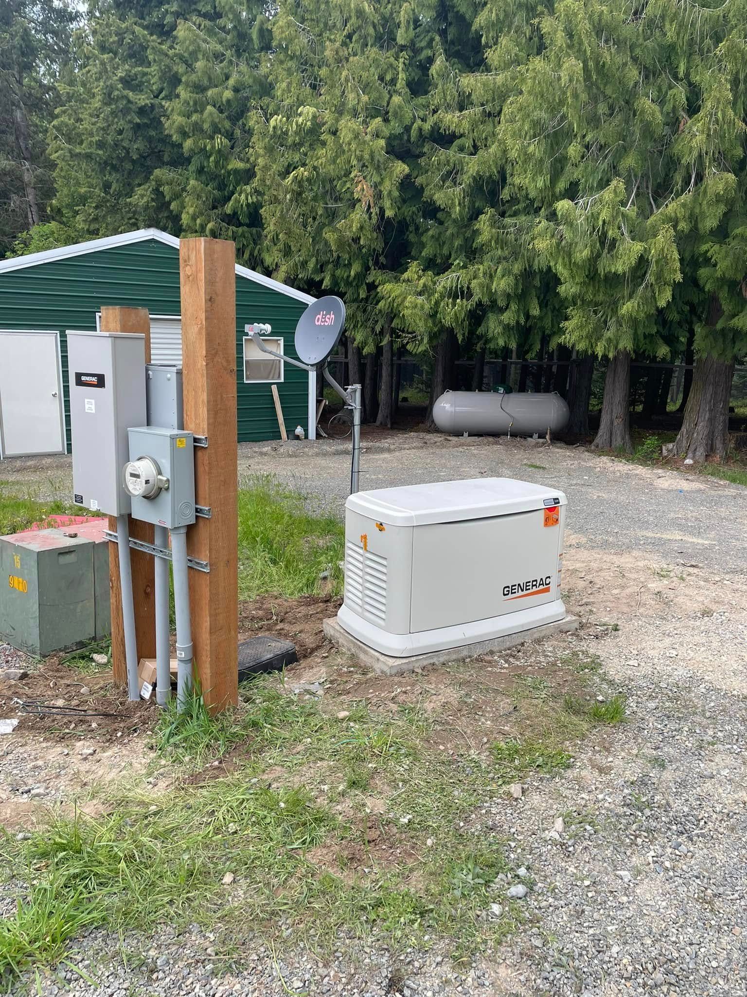 Outdoor utility equipment beside a gravel path, with tanks, a satellite dish, and trees in the background