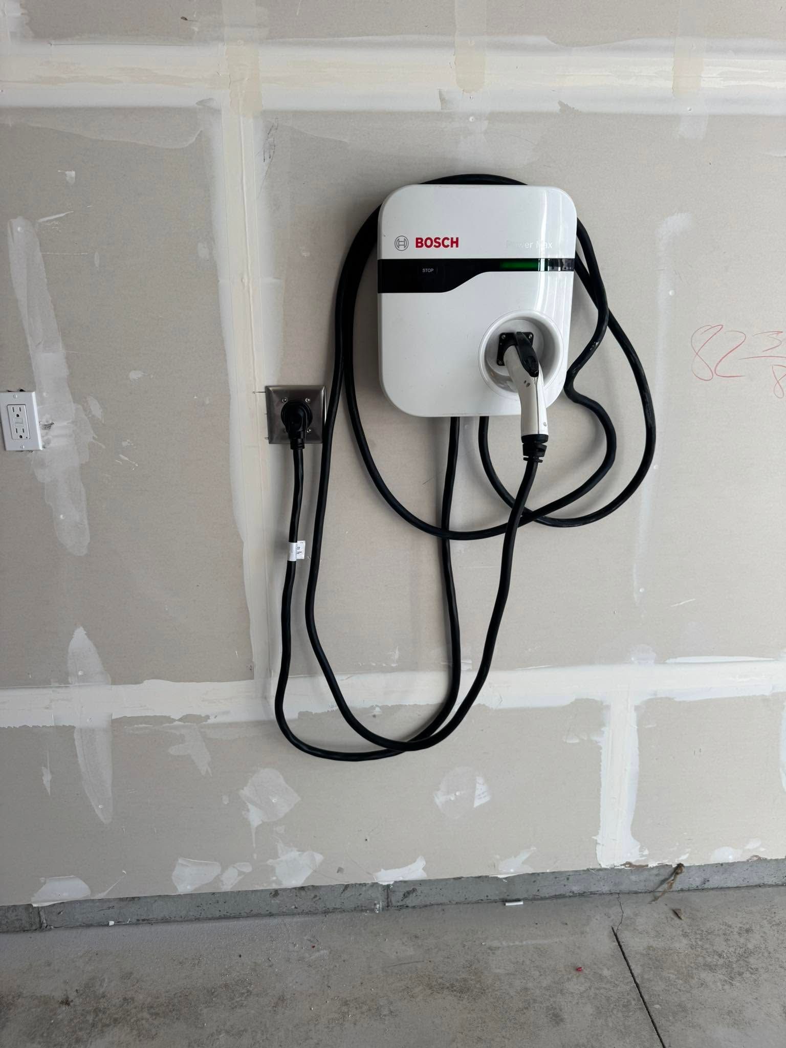 Wall-mounted electric vehicle charger with coiled cable in a garage.