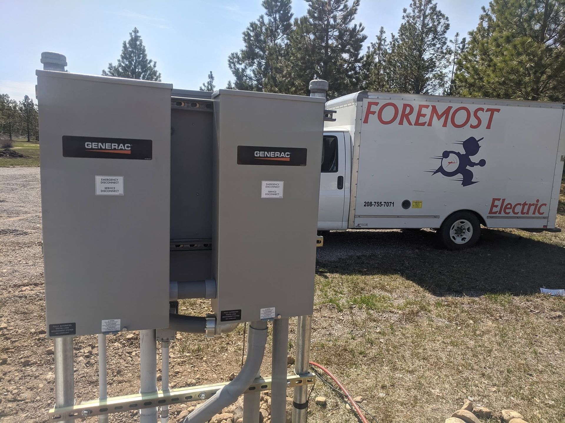 Two gray electrical panels in front of a Foremost Electric service truck outdoors
