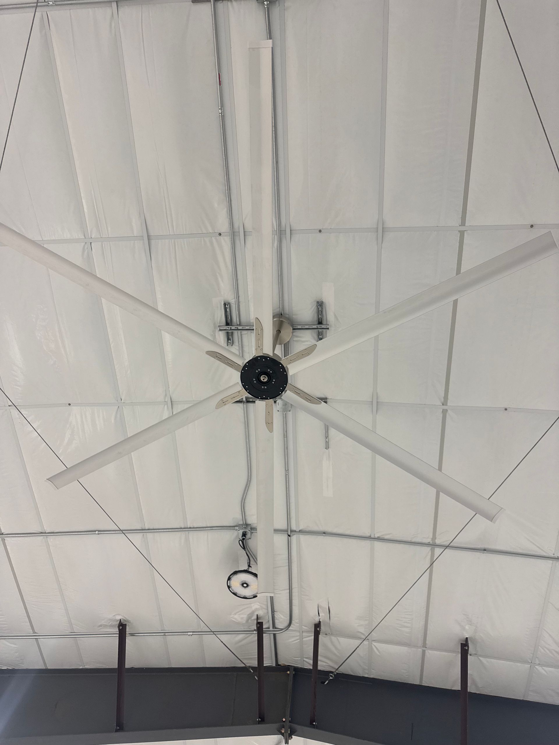 White vaulted ceiling with exposed beams and a central black ceiling fan or light fixture.