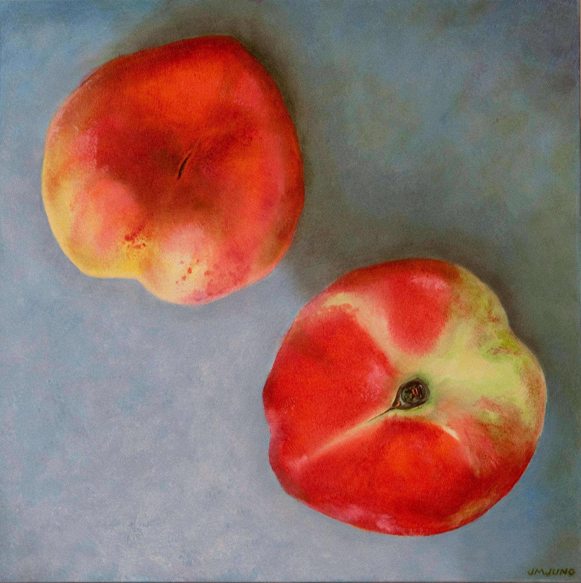 Looking down on two peaches, mostly red. A little yellow against a blue background.
