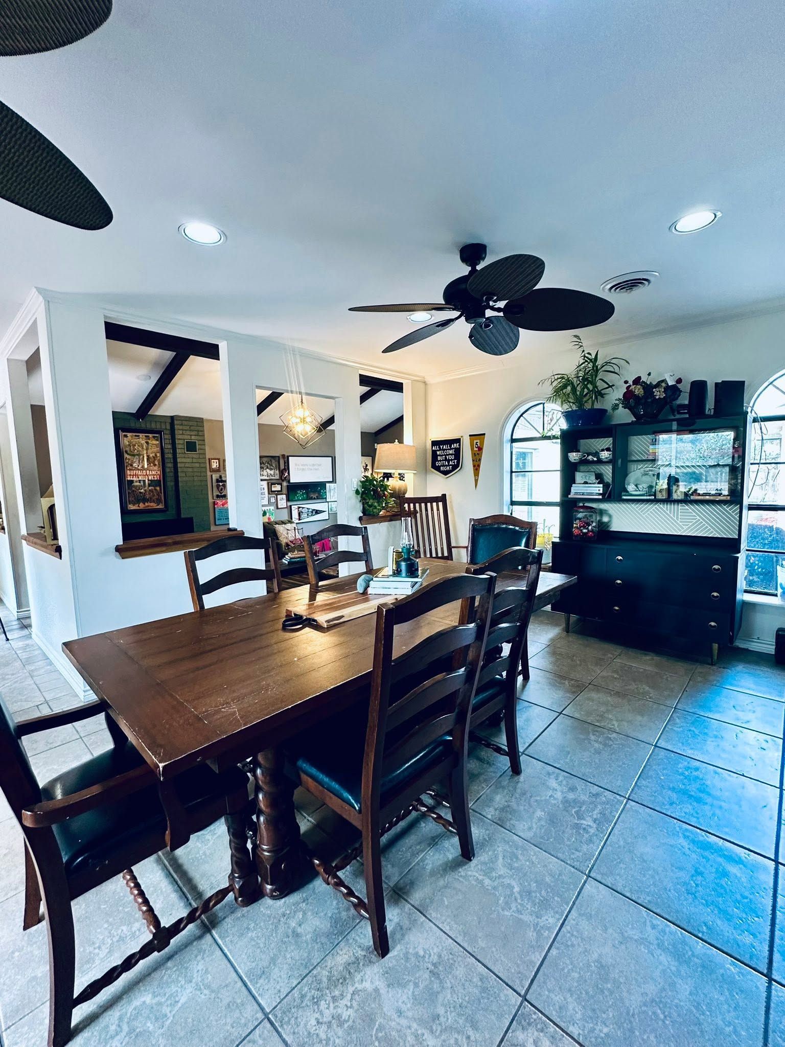 Dining room with dark wood table and chairs, tiled floor, ceiling fans, and a china cabinet in the background