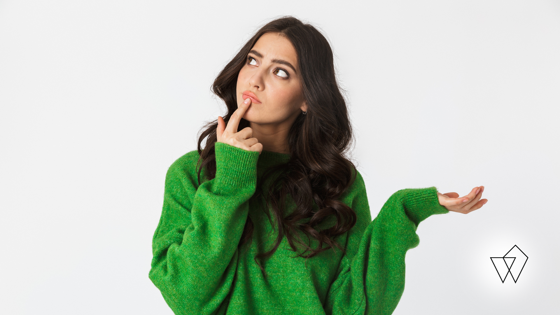 Woman in a green sweater thinking with finger on her lips against a white background