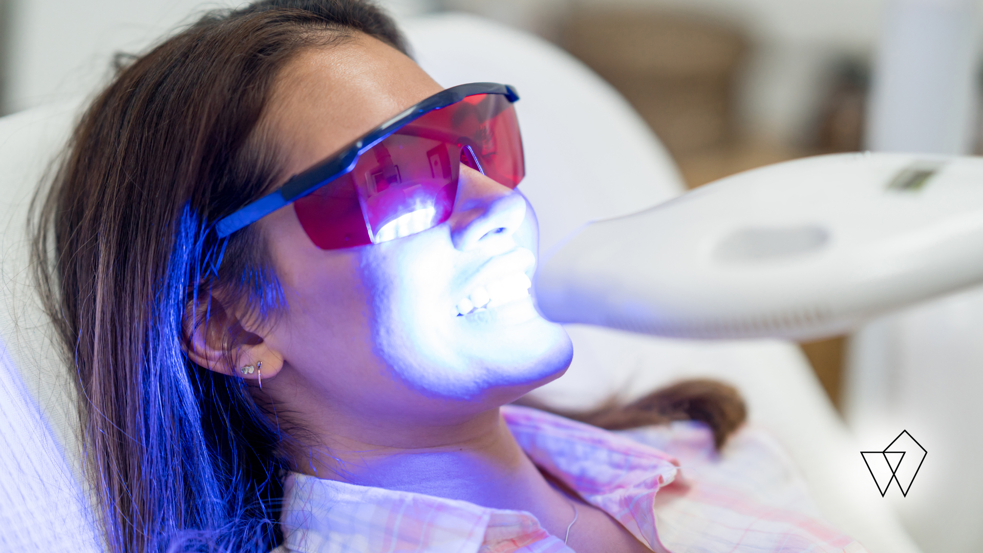Woman receiving blue LED light treatment while wearing protective glasses in a clinic
