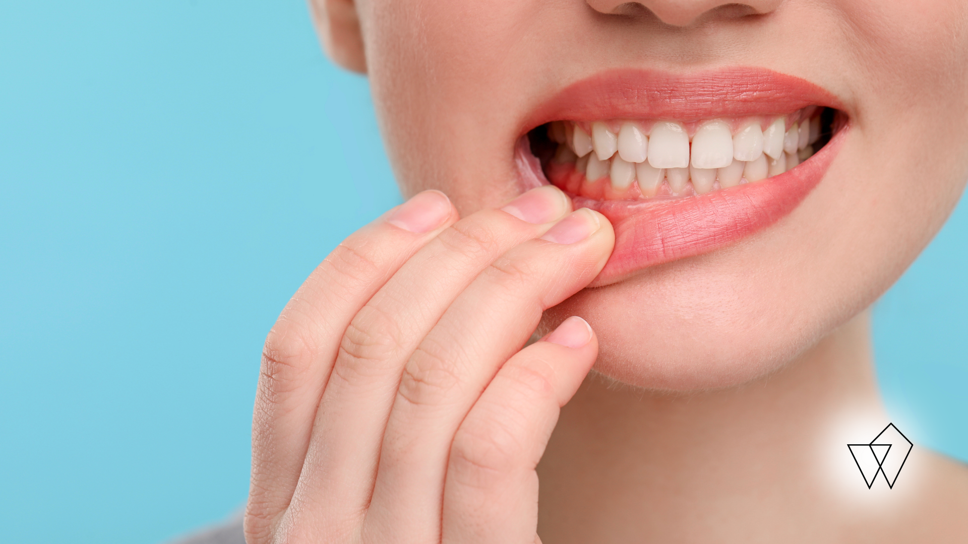 Close-up of lips and teeth as a hand pulls down the lower lip, showing dental checkup on a blue background