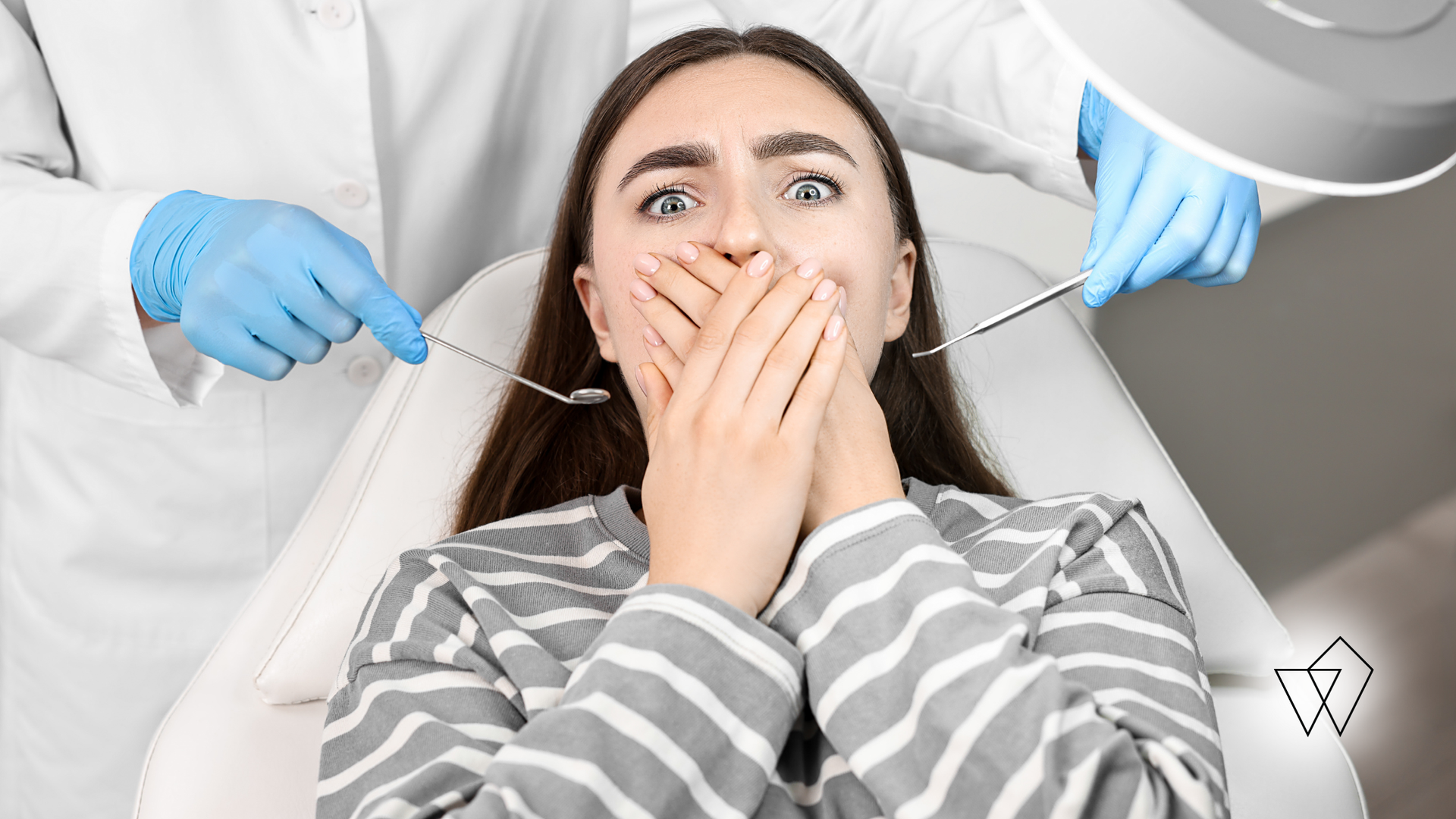Patient covering mouth in a dental chair as gloved dentists work nearby